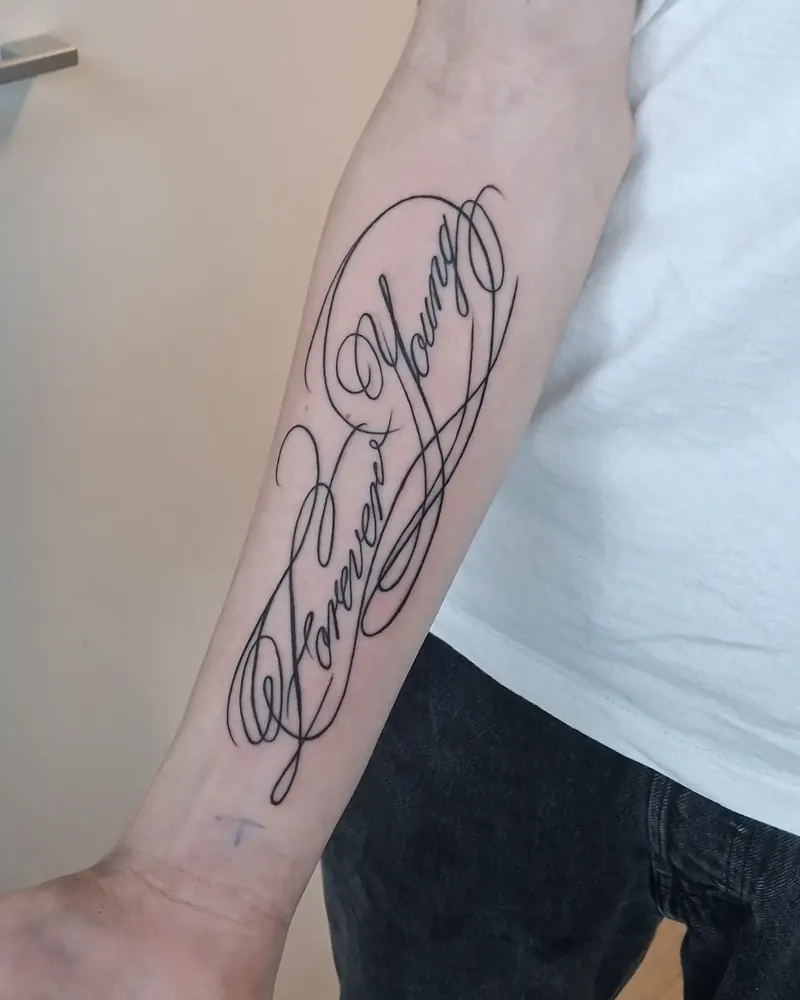Kalligrafisk teksttatovering på underarm